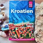 Text: "Kroatien", "Reiseführer für individuelles Entdecken". Abbildung eines Reiseführers mit Küsten- und Stadtansicht.