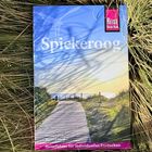 "Spiekeroog", "Reiseführer für individuelles Entdecken". Ein Holzsteg durch Dünen im Sonnenlicht, umgeben von Gras.