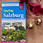 "CityTrip Salzburg" von Margit Brinke und Peter Kränzle, neben goldumwickelten Pralinen mit Mozart-Motiv und pinker Schleife.