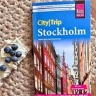 "City|Trip Stockholm" von Stefan Krull und Lars Dörenmeier. Buch auf rundem Knäckebrot, daneben Frischkäse mit Blaubeeren.