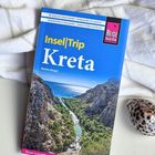 „Insel|Trip Kreta, Markus Bingel“ auf Reiseführer, vor Landschaft mit Schlucht, Meer, Bäumen; rechts eine Muschel.
