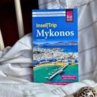 Reiseführer "Insel|Trip Mykonos", türkis-blaues Cover, Stadtansicht mit Hafen und blauen Dächern, Muscheln im Vordergrund.