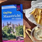 Reiseführer "CityTrip Maastricht mit Lüttich" neben Pommes und einem Schälchen Mayonnaise auf Holzbrett.