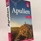 „Apulien“, „mit Ausflug nach Matera“, „Peter Amann“. Sonnenuntergang über einer Stadt auf einem Hügel, blauer Himmel.