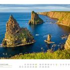 "Schottland" steht im Text. Majestätische Felsen erheben sich aus dem blauen Meer entlang einer steilen Küstenlinie.