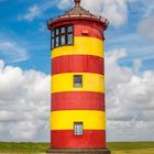 Kalenderblatt September; zeigt den rot-gelb gestreiften Pilsumer Leuchtturm auf grünem Gras vor blauem Himmel.