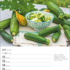 "Juli. Krebs ♋ 21.6.–22.7. Zitat: 'Indem wir die Natur betrachten...' von Adam Heinrich Müller. Zucchini und Blüte auf Tisch."