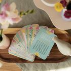 Kartentext: "Fühlt dir Enge in deiner Brust? Meine Mini-Yoga-Übung für jene Tage." Eine Karte mit floralen Motiven, auf einem Holztablett platziert, daneben eine Vase mit Blumen.