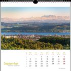 Kalenderseite für September. Foto einer Stadt vor einem See, dahinter Hügel und Berge im Abendlicht.