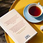 Zitate von Pierre Stutz über Mystik, Buch auf gelbem Tisch, blaue Tasse Tee und eine Schnecke daneben.