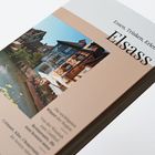 "Essen, Trinken, Erleben Elsass" auf einem Buchcover mit Fachwerkhäusern an einem Fluss.