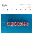 "Oktober KW 40: 4. Montag, 5. Dienstag, 6. Mittwoch, 7. Donnerstag, 8. Freitag, 9. Samstag, 10. Sonntag. Luftaufnahme eines Containerschiffs im blauen Wasser."