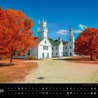 Herbststimmung in Sullivan County, New Hampshire. Weiße Gebäude unter blauem Himmel, umgeben von roten Herbstbäumen.