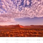 "09. Sanddünen im Sossusvlei, Namib-Naukluft National Park. Hügelige Wüstenlandschaft unter einem Himmel mit rosa Wolken."