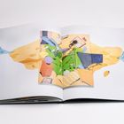 Ein aufgeschlagenes Buch zeigt eine bunte Illustration. Eine Person liegt auf einem grünen Sofa, umgeben von Objekten.