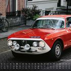 Kalender mit einem roten Alfa Romeo GT Junior. Das Datum ist der 10. Ein Fahrrad steht vor einem Backsteingebäude.