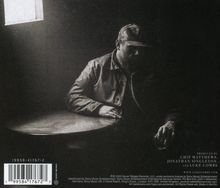 Texte: "Produced by Chip Matthews, Jonathan Singleton, and Luke Combs". Eine Person sitzt allein an einem Tisch in einem dunklen Raum.