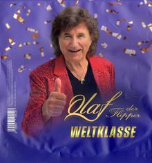 "Olaf der Flipper WELTKLASSE." Ein Mann in glitzernder roter Jacke zeigt Daumen hoch, vor lila Hintergrund mit Konfetti.