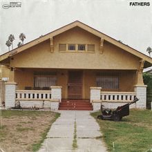 Oben rechts steht "FATHERS". Ein schlichtes, gelbes Haus mit Veranda; davor steht ein Rasenmäher.