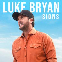 „LUKE BRYAN SIGNS“ steht oben. Ein Mann in oranger Jacke und schwarzer Mütze, lächelt und schaut nach rechts.