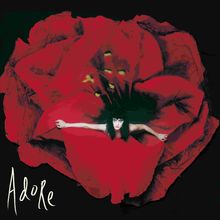 Der Text "Adore" steht unten links. Eine Frau in einem roten Kleid erstreckt die Arme, umgeben von großen roten Blütenblättern.