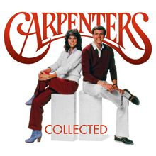 Logo: "Carpenters" und "Collected" in roter Schrift. Zwei Personen sitzen lächelnd auf weißen Blöcken.