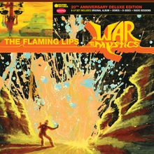 „20th Anniversary Deluxe Edition“, „The Flaming Lips“, „At War with the Mystics“. Bunte, explosive Illustration.