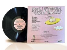 "Jake Mason Trio" Albumcover, Trackliste und ein stilisiertes UFO auf rosa Hintergrund. Vinyl-Schallplatte daneben.