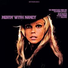"Movin' With Nancy" steht groß über dem Porträt einer Frau mit Hut, blondem Haar, im Fokus eines Scheinwerfers.