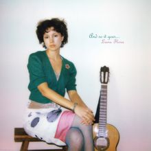 Text: "And so it goes... Liana Flores". Eine Person sitzt auf einer Bank neben einer Gitarre, dezent gekleidet.
