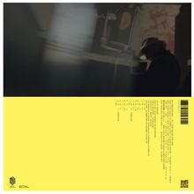 Gelber Hintergrund mit Texten in einer Spalte, darunter "NON SILENT" und "MINI MUSIC." Rechts ein Barcode. Im dunklen Bereich sitzt eine Person mit Hut an einem Schreibtisch.