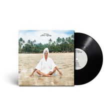 „Achi Osahn, Silver Lining“. Eine Person sitzt meditierend im Bademantel am Strand, umgeben von Palmen.