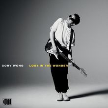 CORY WONG, LOST IN THE WONDER. Ein Mann in weißem T-Shirt spielt Gitarre und schaut nach oben, ein Logo links unten.