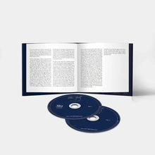 Ein Buch mit Texten ist geöffnet. Darunter liegen zwei CDs mit blauen Hüllen und goldener Schrift.