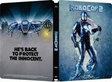 „He's back to protect the innocent.“ Links Roboter durchbricht Wand, rechts stehender Roboter, Titel „RoboCop 2“.