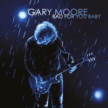 Text: "GARY MOORE BAD FOR YOU BABY". Illustration: Person spielt Gitarre im Regen, beleuchtet von blauem Licht.
