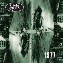Text "ash." in einem schwarzen Oval oben links, "1977" unten rechts. Eine gespiegelte Straßenszene mit Mülleimer.