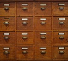 Ein Holzschrank mit 16 kleinen Schubladen. Einige Schilder: "42 Kräuter", "49 Gewürze", "50 Gewürze", "56 Poesien".