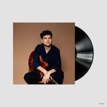 Text "Vinyl". Ein Mann mit dunklem Hemd, sitzt mit einer Gitarre. Eine Schallplatte ist neben ihm zu sehen.