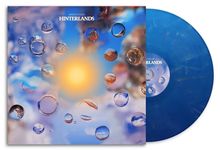 Der Text "GREEN-HOUSE HINTERLANDS" steht über einer blauen Platte mit Wassertropfen und einem orange leuchtenden Zentrum.