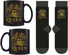 Der Text "QUEEN" steht auf zwei schwarzen Tassen und Socken, verziert mit einem goldenen Wappen aus Löwen und einem Phönix.