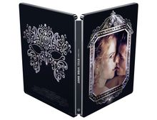 Ein aufklappbarer schwarzer Steelbook mit dem Text "EYES WIDE SHUT". Links dekorative Maske, rechts nahes Paar in verziertem Rahmen.