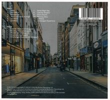 Ein Stadtbild mit zweistöckigen Läden, Kopfsteinpflaster und einer leeren Straße.