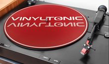 "VINYLTONIC" steht auf einer roten Plattenteller-Matte eines Plattenspielers. Tonearm und Bedienelemente sind sichtbar.