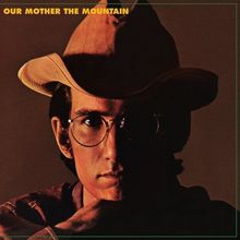 Text: "OUR MOTHER THE MOUNTAIN". Eine Person im Schatten, trägt einen Cowboyhut und eine Brille, ernstes Gesicht.