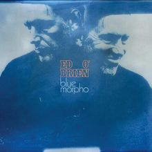 Text: "Ed O'Brien, blue morpho". Zwei blaue Porträts einer Person, die nachdenklich und lächelnd wirkt.