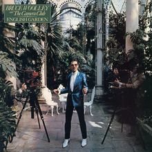 Text: "BRUCE WOOLLEY and The Camera Club ENGLISH GARDEN". Ein Mann in blauem Anzug steht zwischen Pflanzen.