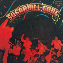 "SUGARHILL GANG" in leuchtenden Buchstaben über einer feiernden Menschenmenge, bunte Dekorationen im Hintergrund.