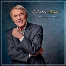 "Salvatore Adamo. Mes Chansons. Ma Vie." Ein älterer Mann in einem eleganten Anzug lächelt freundlich.
