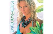 Links der Text "Kate Ryan alive". Frau mit lockigem Haar, auffällige Halskette, grünes Oberteil, von Pflanzen umgeben.